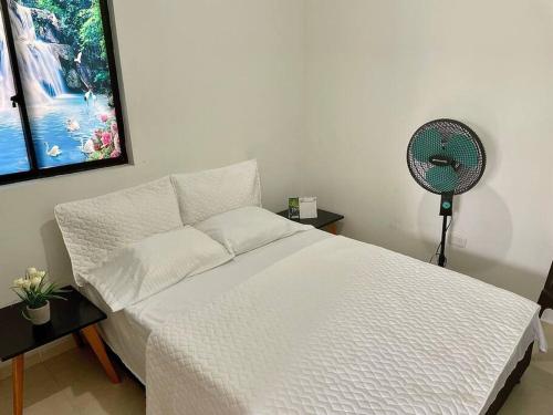 a bedroom with a white bed and a fan at Reserva Quindiana in La Tebaida