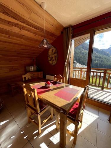 a wooden table and chairs in a room with a window at T3 Champagny-en-Vanoise avec terrasse plein sud in Champagny-en-Vanoise