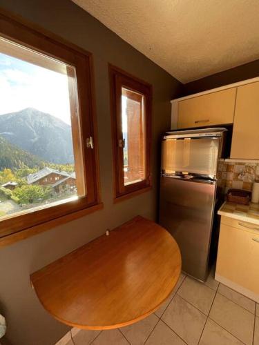 a kitchen with a wooden table and a refrigerator at T3 Champagny-en-Vanoise avec terrasse plein sud in Champagny-en-Vanoise