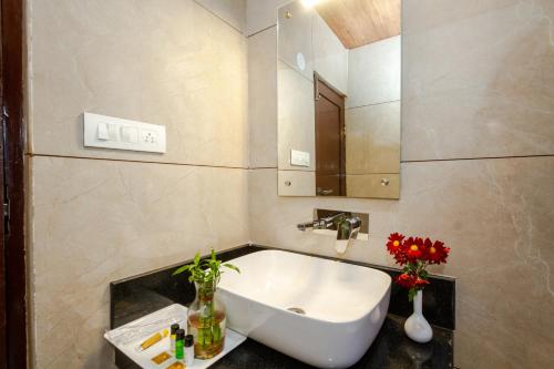 a bathroom with a sink and a mirror and flowers at Tripli Hotels Drilbu Manali in Manāli