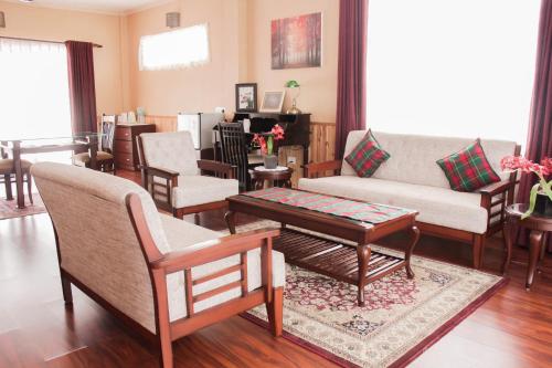 a living room with a couch and chairs and a table at Windermere Inn in Shillong