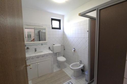 a white bathroom with a toilet and a sink at Apartments Noel in Zambratija