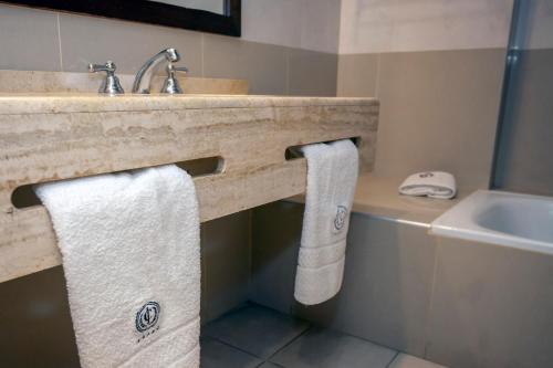 a bathroom with a sink and two white towels at Hotel Catalinas Tucuman in San Miguel de Tucumán