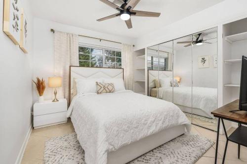 a white bedroom with a bed and a mirror at Lovely 2-Bdr w/Patio, Lake Park! in Naples