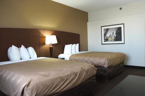 a hotel room with two beds and a lamp at American Inn & Suites in Waterford