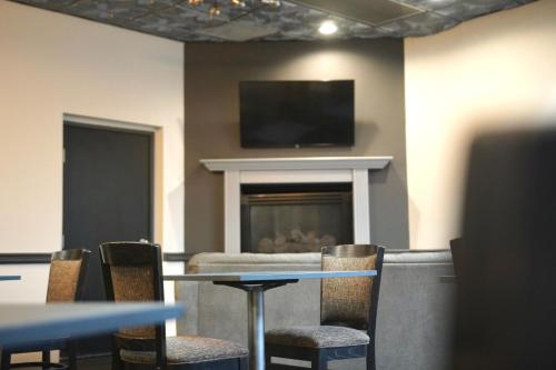 a room with a table and chairs and a fireplace at American Inn & Suites in Waterford
