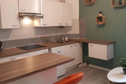 une cuisine avec des armoires blanches et un comptoir en bois dans l'établissement Appartement Canne 1 chambre - 21JOFFRE, à Cannes