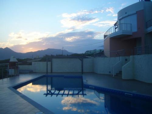 a swimming pool on top of a building with the sunset at Seascape in Tersanas
