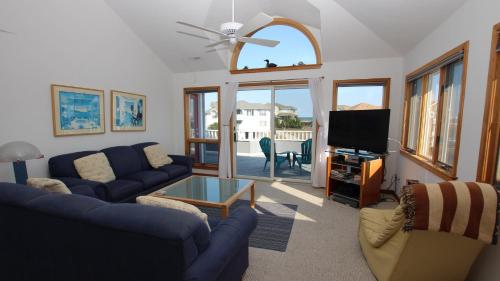 a living room with a blue couch and a tv at Semi-Oceanfront, Private Pool, Hot Tub, Close to Beach Access, GF2, Touch of Grey in Sanderling