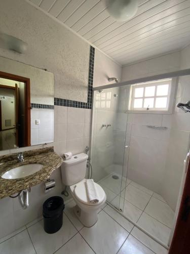 a bathroom with a toilet and a shower and a sink at Pousada Jordão in Campos do Jordão