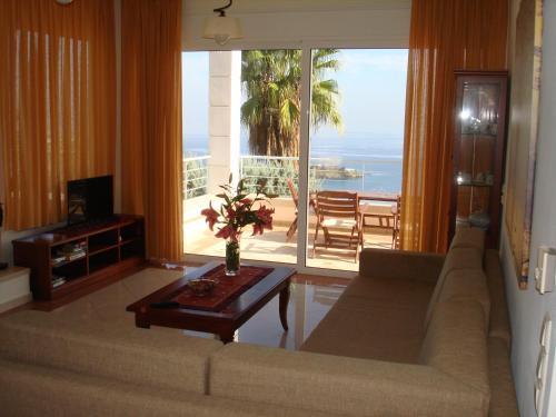 een woonkamer met een bank en uitzicht op de oceaan bij Agnanti Villas in Agia Pelagia