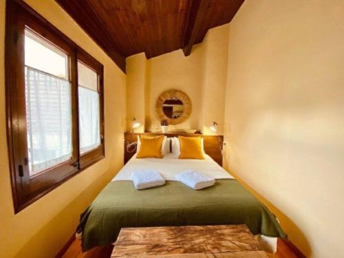 Un dormitorio con una cama con almohadas amarillas y una ventana en La Cabaña de Llívia, Cerdanya, Puigcerdà., en Llivia
