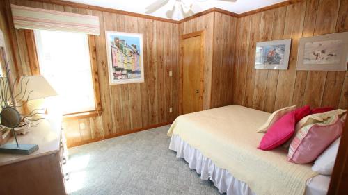 a bedroom with wooden walls and a bed with pink pillows at Oceanside, Friday to Friday, Sun Decks, Close to shopping, KD22, Summer Reflections in Kill Devil Hills