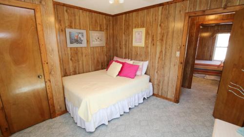 a small bedroom with a bed with pink pillows at Oceanside, Friday to Friday, Sun Decks, Close to shopping, KD22, Summer Reflections in Kill Devil Hills