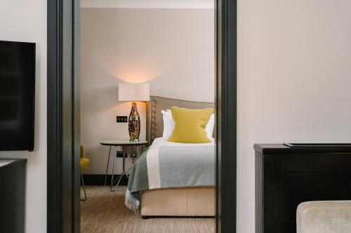 a bedroom with a bed with a yellow pillow on it at Royal Berkshire in Ascot