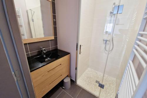 La salle de bains est pourvue d'un lavabo et d'une douche avec un miroir. dans l'établissement Ty Colo ✿ maison familiale classée, proche Brest, à Saint-Renan