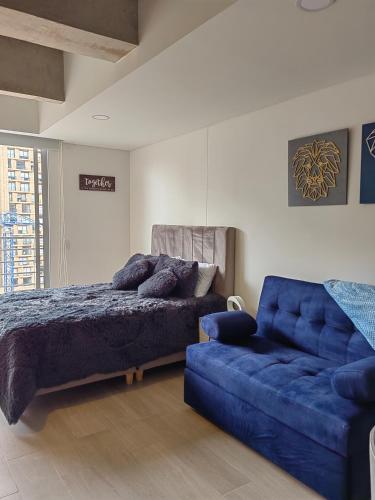 1 dormitorio con 1 cama azul y 1 sofá azul en Apartamento Chic en el corazón de Bogotá, en Bogotá