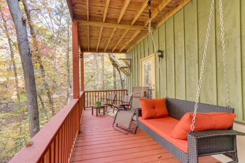 a porch swing with orange pillows on a green house at Quiet Murphy Hideaway with Decks and Outdoor Fireplace in Murphy