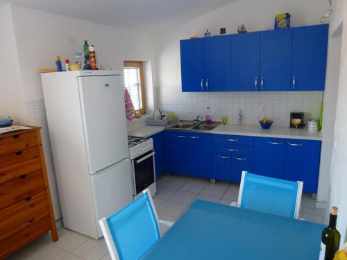 a kitchen with blue cabinets and a white refrigerator at Apartments Kujundžić in Kaprije