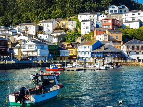 a boat in a body of water with houses at El Jardín y Mar in O Barqueiro