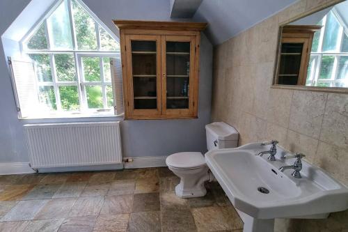 a bathroom with a sink and a toilet andwindows at Spacious stone cottage w/ extensive private garden in Bolton