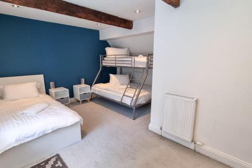 1 Schlafzimmer mit 2 Etagenbetten und einer blauen Wand in der Unterkunft Spacious stone cottage w/ extensive private garden in Bolton