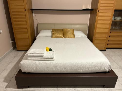 a bed with white sheets and gold pillows at Luminoso Monolocale zona servita in Legnano