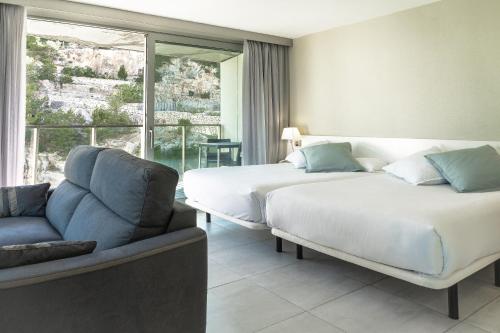 a bedroom with two beds and a couch and a window at Ágora Spa & Resort in Peniscola