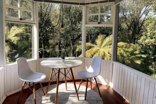 einen Tisch und zwei Stühle in einem Zimmer mit Fenstern in der Unterkunft Blue House em Condomínio Fechado in Gramado