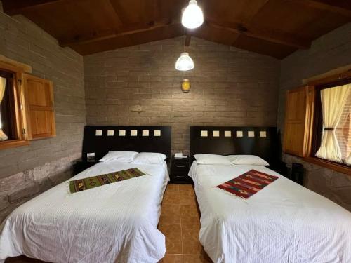 2 Betten in einem Zimmer mit weißer Bettwäsche in der Unterkunft HOTEL Y CABAÑAS MOUNTAIN LODGE in Zacatlán