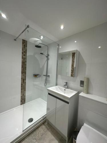 baño blanco con ducha y lavamanos en Le Friquet Hotel en Castel