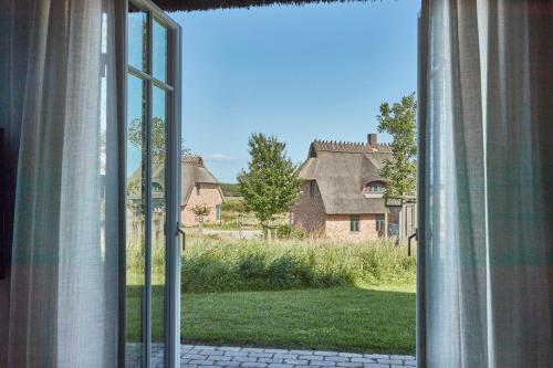 ein offenes Fenster mit Blick auf einen Hof in der Unterkunft Reetdorf Geltinger Birk Atelierhaus Sandbank in Nieby