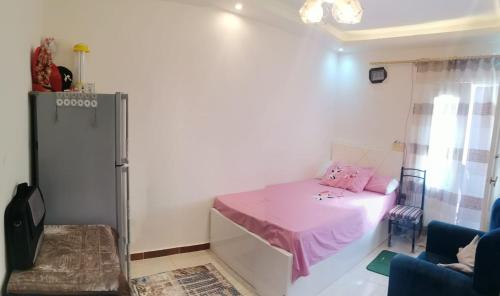 um pequeno quarto com uma cama rosa e uma cadeira em الإسكندرية طوسون شارع المستشارين بجوار فتح الله ماركت em Abū Qīr