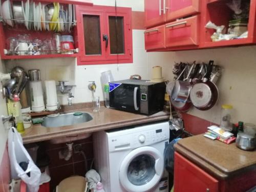 a kitchen with a washing machine and a microwave at الإسكندرية طوسون شارع المستشارين بجوار فتح الله ماركت in Abū Qīr