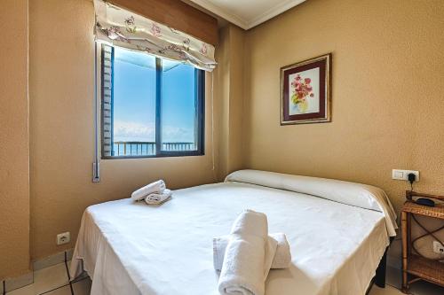 een slaapkamer met een bed en een raam met handdoeken bij Encantador apartamento con vistas al mar y AC in San Pedro del Pinatar