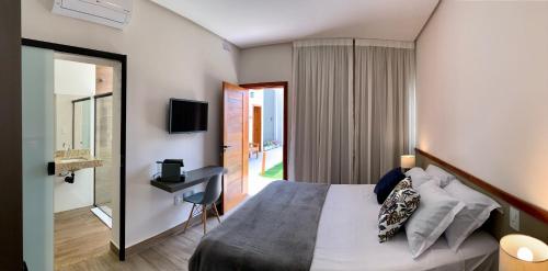 a bedroom with a bed and a desk and a window at Pousada Saudadocê in São José da Barra