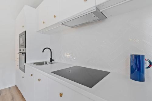 - une cuisine blanche avec un évier et une tasse bleue dans l'établissement Contemporain 1BR Rétro Chic Quartier Bonnevoie, à Luxembourg