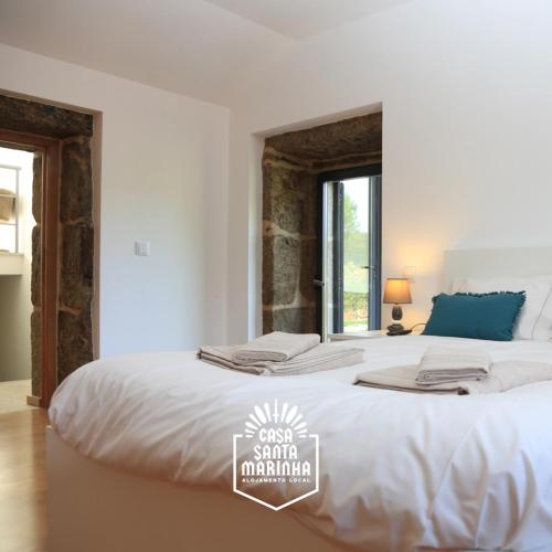 a white bedroom with a large bed and a window at Casa Santa Marinha in Paredes de Coura