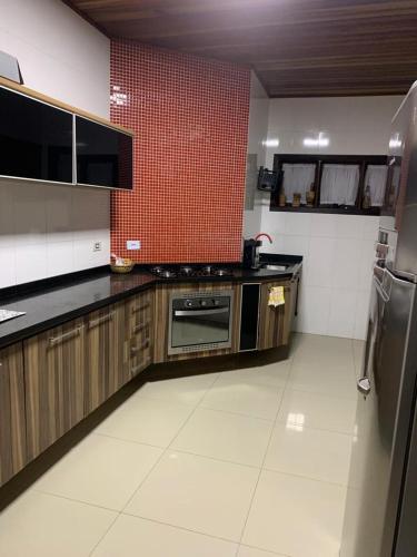 una cocina con armarios de madera y una pared de baldosas rojas. en 3 Pinheiros en Campos do Jordão