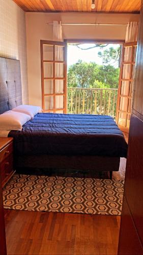 1 dormitorio con cama y ventana grande en 3 Pinheiros en Campos do Jordão