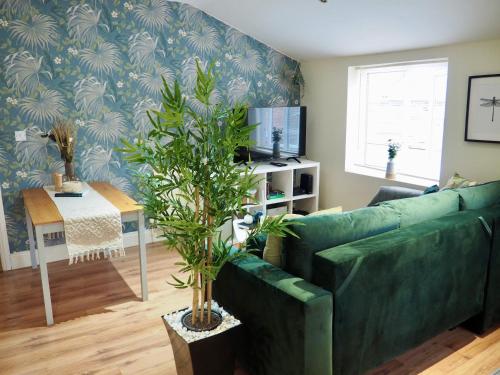 ein Wohnzimmer mit einer grünen Couch und einer Pflanze in der Unterkunft Spacious & Bright Flat, Cowley Rd in Oxford