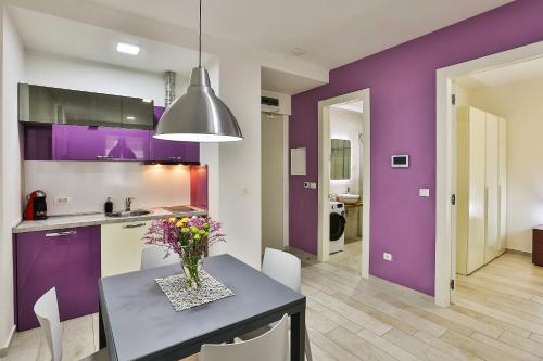 a kitchen with purple walls and a table with flowers on it at Royal Gardens Paradise in Budva
