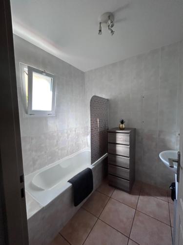 een badkamer met een bad en een wastafel bij Logement entier : Maison in Saleilles