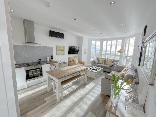 eine weiße Küche und ein Wohnzimmer mit einem Tisch in der Unterkunft St Annes Beach Apartments in Lytham St Annes