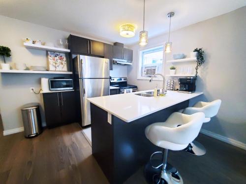 una cucina con lavandino e bancone con due sgabelli di *NEW: Stylish Wortley 1BR Suite a London