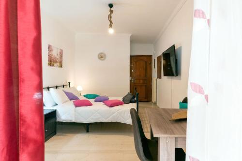 um quarto com uma cama com almofadas vermelhas e uma mesa em Maria's Apartment δίπλα στο Νοσοκομείο Παίδων και στο Λαϊκό em Atenas