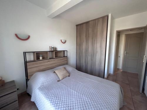 une chambre avec un lit blanc avec une tête de lit en bois dans l'établissement Logement entier : Maison, à Saleilles