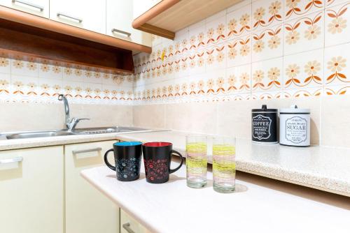uma cozinha com duas canecas e copos num balcão em Maria's Apartment δίπλα στο Νοσοκομείο Παίδων και στο Λαϊκό em Atenas