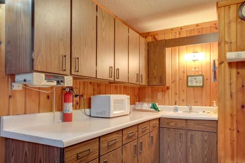 a kitchen with wooden cabinets and a microwave at Iron River Vacation Rental with Ski Slope Views! in Iron River