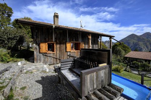 an old wooden house with a pool in front of it at Chalet "Baita Cavacca" in Crone
